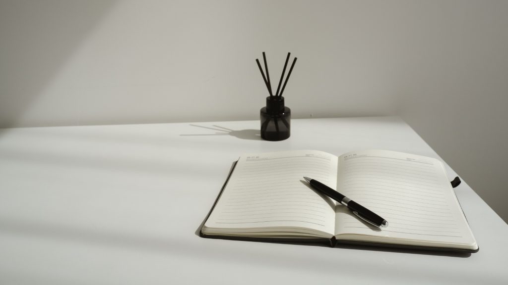 Bureaudetail met notitieboek, pen en geurstokjes